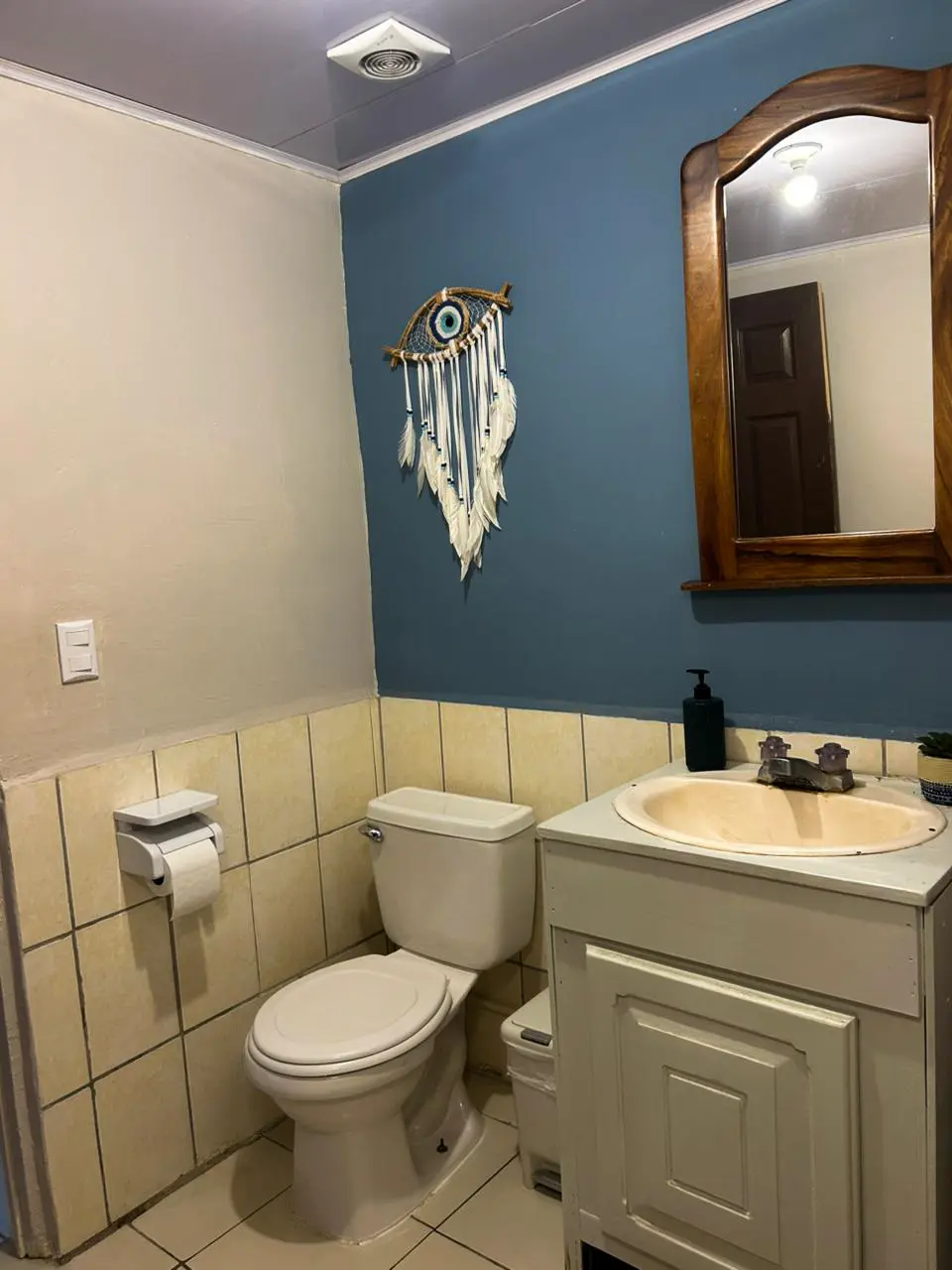 Detalle de baño del hostel con decoración de atrapasueños y ojo turco en pared azul.