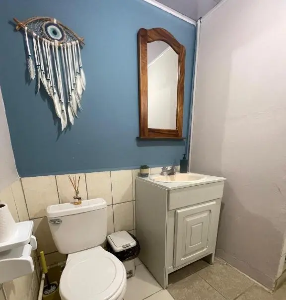 Vista completa del baño del hostel de chicas, limpio, con pared azul y azulejos.