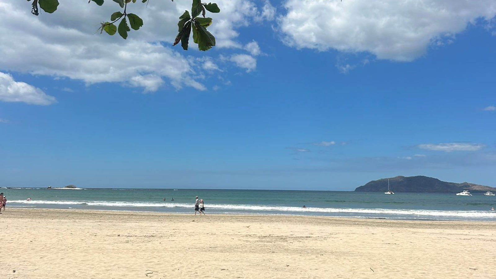 Woman walking alone along Tamarindo beach at sunset, surfboard under her arm