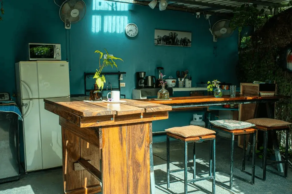 Cocina al aire libre comunitaria con isla de madera rústica y barra de bar, ambiente relajado para socializar.